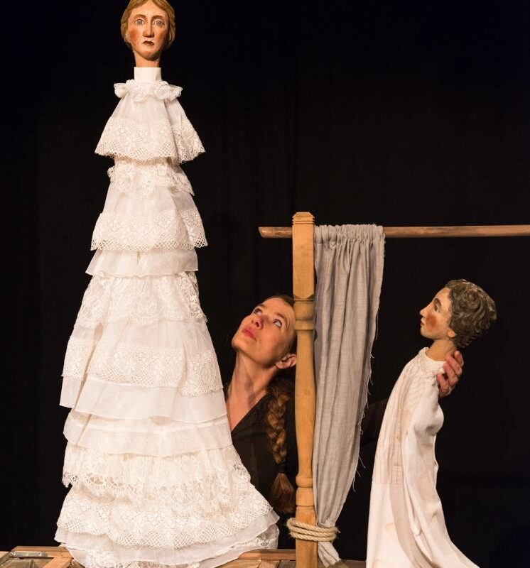 Frau mit zwei Theaterpuppen, schwarzer Hintergrund